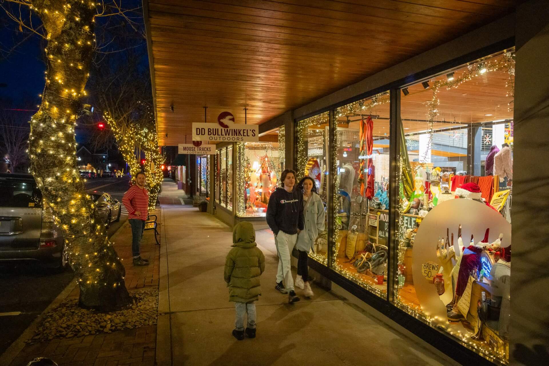 People on the street shopping and admiring the holiday window display in Downtown Brevard