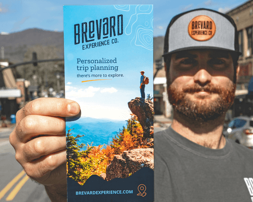 Man holding Brevard Experience Company trip planning brochure in Downtown Brevard