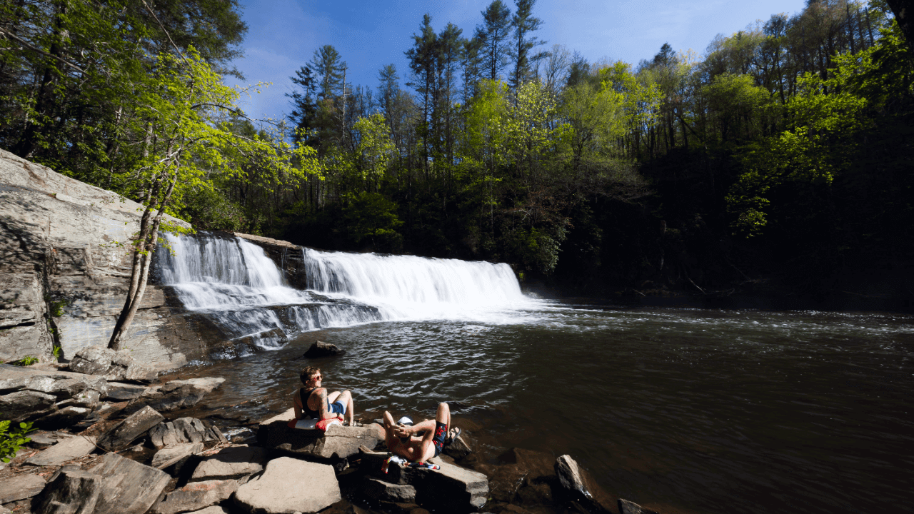 Couple sitting on the rocks at Hooker Falls in DuPont State Recreational Forest near Cedar Mountain NC