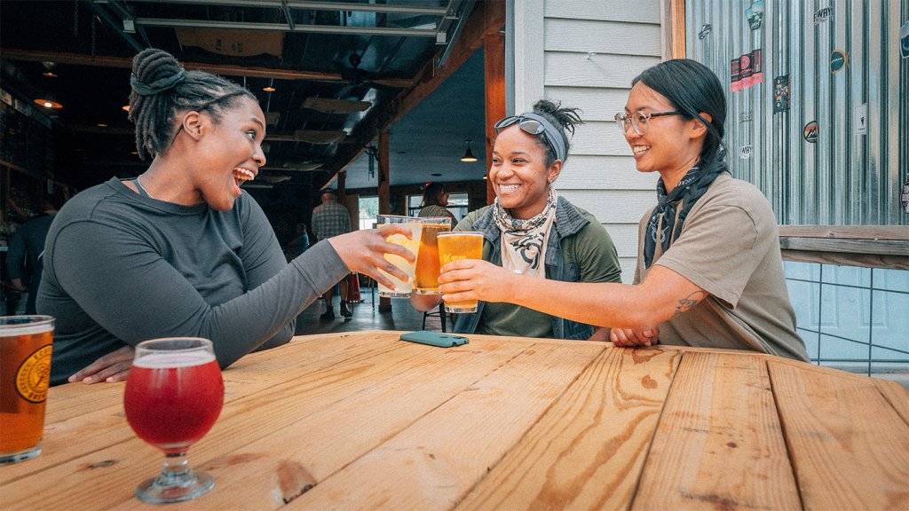 Three women have a beer at a mountain bike shop that has a taproom inside